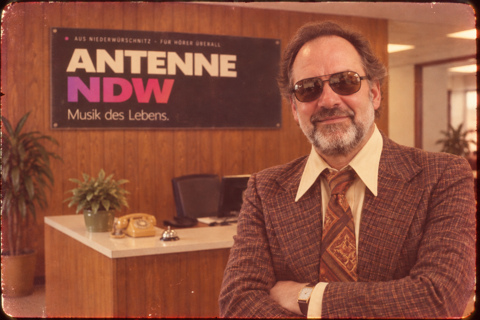 Büroszene mit dem Schild ANTENNE NDW – Musik des Lebens